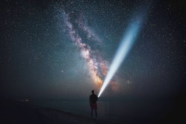 Yalnız bir gözlemci büyüleyici Samanyolu 'nun altında sahilde duruyor. Bir el feneri karanlığı delip geçer keşfedilmemiş bir evreni ortaya çıkarır..