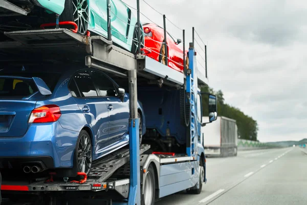 Car carrier trailer truck with brand new exotic luxury sport cars for a racing championship, car show or sale. Car transporter trailer loaded with italian car. Two-level modular hydraulic semi-trailer