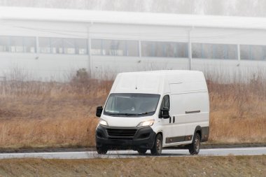 Kendi dağıtım servisini bu beyaz minibüsün maketi ile tasarla. İş logonuz ve isminizle kişiselleştirmeniz için boş bir paket. Farklı manzaralı bir ticari araç yolda izole edilmiş..