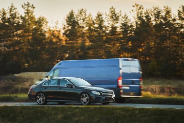 Otoyolda giden araba, bulanık doğal manzara arka planına sahip. Günbatımında otoyolda izole edilmiş modern bir araç..