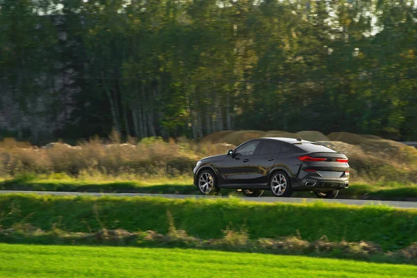 Alt kompakt bir SUV arabası arka planda muhteşem bir günbatımı ve dağlarla manzaralı kırsal bölgeleri keşfediyor..