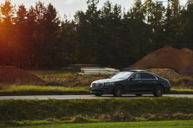 Günbatımı ve orman geçmişi olan lüks spor bir arabada hız yapmak. Entellektüel pahalı araba yolda. Otobanda lüks ve lüks bir araba var..