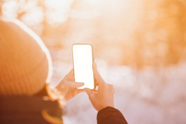 Kadınların elinde akıllı telefon maketi. Kışın bir parkta doğa fotoğrafçılığını seviyor..
