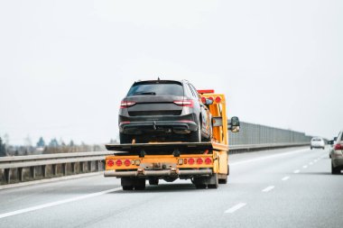 Acil durum yol yardımı yolda. Çekici yolda bozuk bir SUV taşıyor..