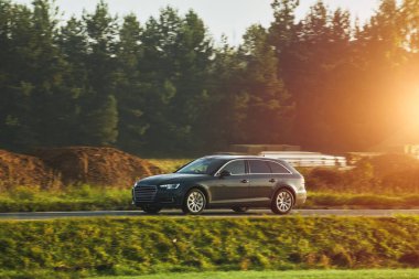 Alacakaranlıkta modern bir araba sürüyorum. Ormanın ve yolun manzaralı manzarası maceraperest yolcuları bekliyor..