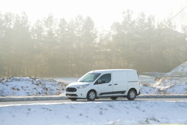 Çarpıcı bir günbatımı ve ormanı olan virajlı bir yolda hızlı giden bir araba.