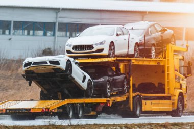 Yarışa ya da göz kamaştırmaya hazır yepyeni egzotik spor arabalardan oluşan bir filo. Onları otoyolda güvenli ve hızlı bir şekilde taşıyan iki katlı hidrolik bir karavana yükleniyorlar..