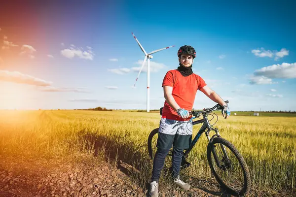 A Rider and His Bike in Front of Wind Turbines