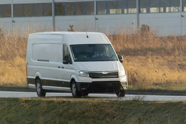 stock image A white van with a blank wrap for your business branding and delivery service. Isolated mockup of a commercial vehicle on the road.