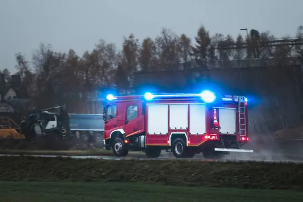 An emergency vehicle drives fast on a road. a firetruck carrying firefighters and fire equipment are on their way to a fire or an accident. The siren sounds as the vehicle moves through the traffic