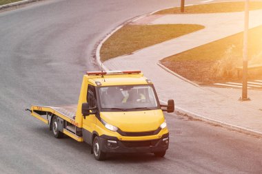 Şehir caddesinde turuncu bir çekicinin ön görüntüsü. Kamyonu ve vinci var. Şehir caddesinde bozulmuş bir arabanın turuncu bir çekicinin yardımına ihtiyacı var..