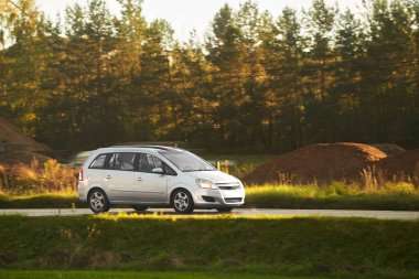 Günbatımında otoyolda izole edilmiş modern bir araç. Sunny Highway 'de lüks bir arabayla yaz tatilinin tadını çıkarıyorum.