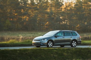 Otoyolda giden araba, bulanık doğal manzara arka planına sahip. Günbatımında otoyolda izole edilmiş modern bir araç..