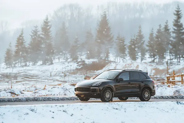 Luxury Performance Meets Winter Terrain. Black German SUV Embraces the Snowy Road.