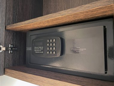Dolaptaki bir rafta küçük bir dijital kasa. Evde ya da otelde güvende. Zengin bir evde kasayı aç. Otel odasında bir kasada. Para, mücevher ve belgeler için güvenli depolama kavramı
