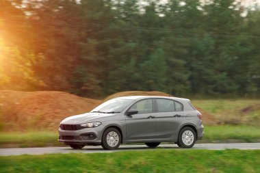 Otoyolda giden araba, bulanık doğal manzara arka planına sahip. Günbatımında otoyolda izole edilmiş modern bir araç..