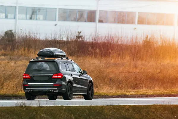 stock image Expensive family SUV with Luggage box mounted on the roof. Extra Capacity for the Road. Black SUV with Roof Rack.