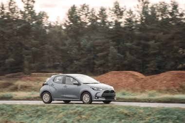 Otoyolda giden araba, bulanık doğal manzara arka planına sahip. Günbatımında otoyolda izole edilmiş modern bir araç..