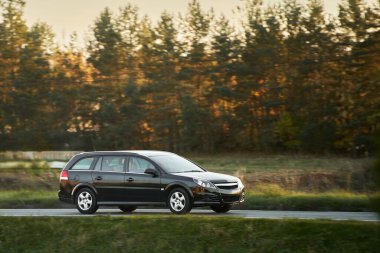 Güzel bir ormanla çevrili, Manzaralı bir yolda giden bir araba.