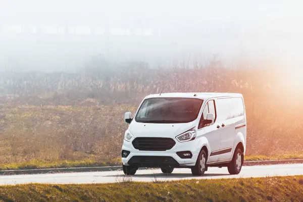 stock image delivery van carries parcels along a sunlit road, ensuring timely service and customer satisfaction.