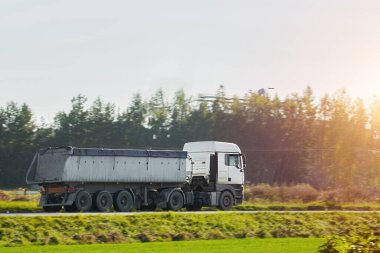 Otoyoldaki nakliye kamyonu bir çöp konteynırında inşaat malzemeleri teslim ediyor.