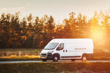 Teslimat minibüsü güneşli bir yol boyunca paketler taşır, tam zamanında hizmet ve müşteri memnuniyetini sağlar.
