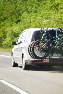 Anayolda monte edilmiş bisiklet kuyruğu taşıyan modern aile arabasının arka görüntüsü.