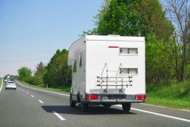 Eğlence aracı güneşe doğru giden manzaralı bir otoyolda, umut verici bir macera ve açık yolun keyfi ile seyahat ediyor.