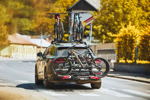 Expensive luxury SUV car with bicycles mounted on roof rack. Expensive electric mountain bikes transported by german made modern sporty truck