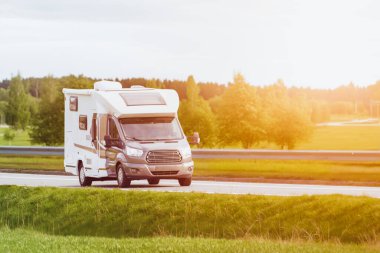 Motorlu ev, dağ zeminli çarpıcı bir gölün yanından geçiyor.