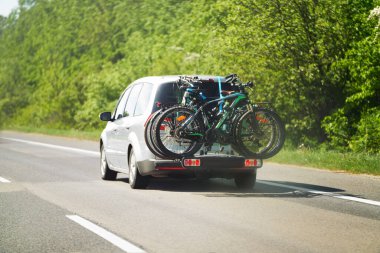 Arka bisikletli bir taşıma aracına monte edilmiş bisikletle otoyol boyunca seyahat eden bir araç..
