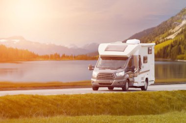 Motorlu ev, dağ zeminli çarpıcı bir gölün yanından geçiyor.