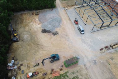 Kazı makinesi ve malzemelerle kırsal inşaat alanının hava görüntüsü.
