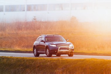 Zarif siyah SUV manzaralı yeşil kırsal alanda sürüyor.