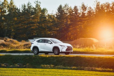 Lüks araba manzaralı kırsal yolda hızla ilerliyor.