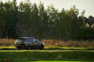 Parlak taşra otoyolunda gezen lüks bir araç.