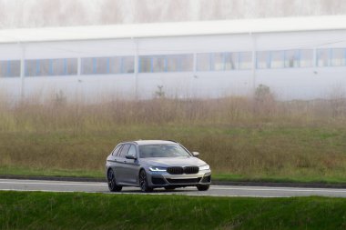 Manzaralı orman yolunda giden şık bir araba.