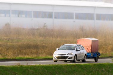 Karavanlı araba güneşli kırsal yolda.