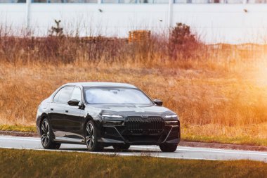 Manzaralı orman yolunda giden şık bir araba.