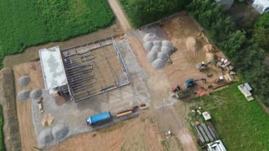 Kazı makinesi ve malzemelerle kırsal inşaat alanının hava görüntüsü.