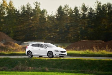 Şatafatlı araba gün batımında otoyolda ilerliyor.