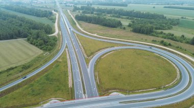 Çevresi tarım arazileriyle çevrili otoyol kavşağının havadan çekilmiş fotoğrafı.