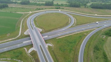 Arabalar ve yeşil manzaralı kırsal otoyol kavşağının yüksek görüntüsü