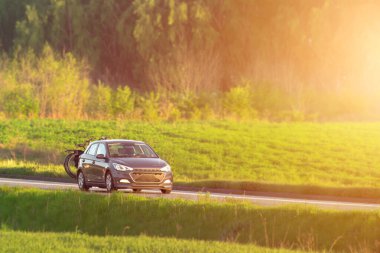 Arka rafta bisikleti olan taşra yolundaki araba.
