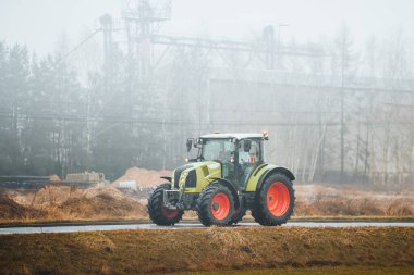 Modern yeşil traktör kırsal sisli yolda sürüyor