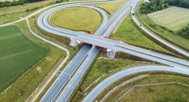 Çevresi tarım arazileriyle çevrili otoyol kavşağının havadan çekilmiş fotoğrafı.