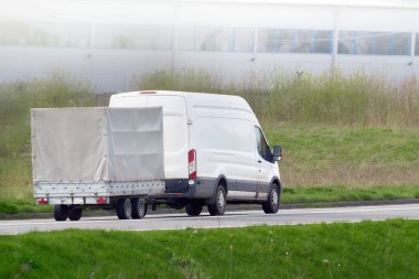 Güneşli kırsal yolda beyaz araba çekici römorku