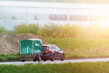 Araç yolda küçük bir römorku çekiyor.