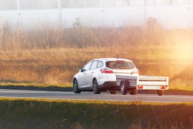 Güneşli kırsal yolda araba nakliye karavanı