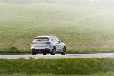 Dağ manzaralı kırsal yolda beyaz lüks SUV.